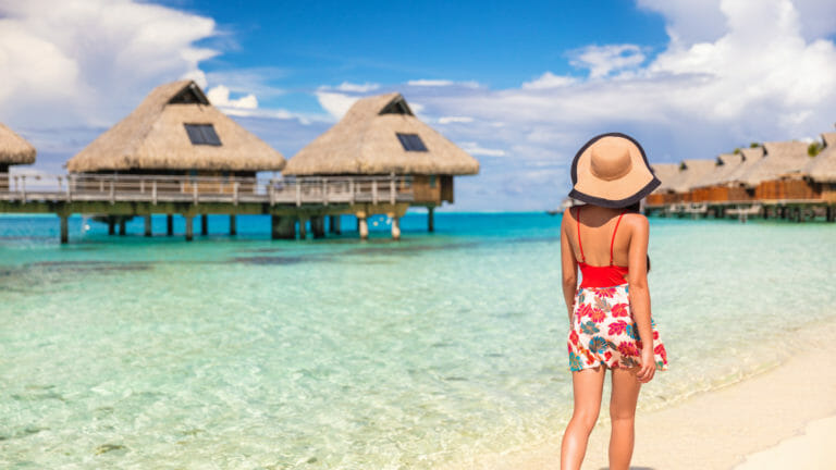 woman at beach with overwater bungalows in bora bora